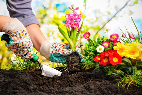 Gardener wearing protective clothing and using battery-powered equipment